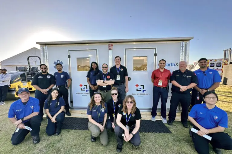 Group of emergency responders posing in front of trailers.